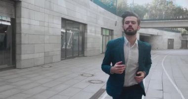 Genç işadamı koşar. Kendine güvenen adam buluşmaya geç kaldı. Takım elbiseli başarılı bir adam modern binanın yakınında koşuyor. Randevu için acele eden yakışıklı adam..