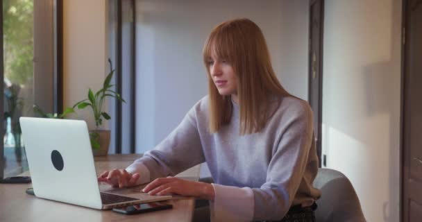 Spännande ung blond kvinna vinnare tittar på bärbar dator firar online framgång sitter på café — Stockvideo