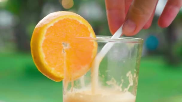 Крупним планом свіжий апельсиновий сік у склянці на зеленому фоні — стокове відео