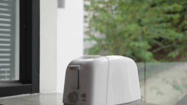 Eller ekmek kızartma makinesine ekmek koyar ve tost makinesini açar. Mutfak gereçleriyle kahvaltı hazırlıyorum.