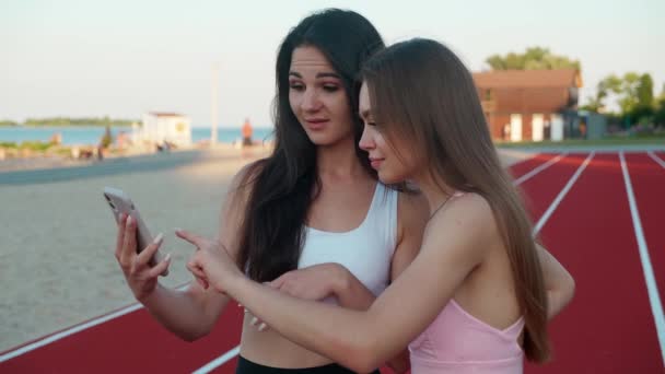 Дві жінки цікаво дивляться на екран смартфона . — стокове відео