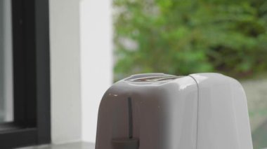 Tost makinesinde iki parça ekmek. İki büyük el bir parça ekmek çıkarır. İki el ekmeği yakın plan çeker.