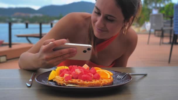 Mujer fotografiando comida en smartphone. Linda chica haciendo foto de gofres y frutas — Vídeos de Stock