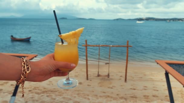 Самка держать в руке желтый лимонад или сок свежий, на берегу моря, летний серфинг волна фон освежающий напиток расслабиться позитивный отдых настроение вид сверху — стоковое видео