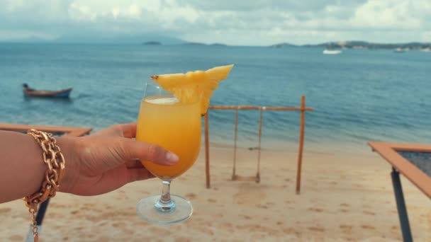 Vrouw houden in de hand gele ananas cocktail, aan zee kust, zomer surf golf achtergrond verfrissend drankje ontspannen positieve stemming vakantie — Stockvideo