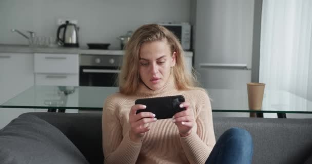 Akıllı telefonuyla video oyunu oynayan genç bir kadın oyunu kaybedince sinirleniyor. — Stok video