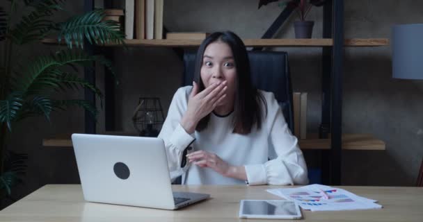 Mulher de negócios asiática surpreendida olha para a câmera de surpresa e diz que sim enquanto está sentado no escritório. Uma estudante chocada em camisas brancas formais se alegra com a boa notícia, dentro de casa. — Vídeo de Stock