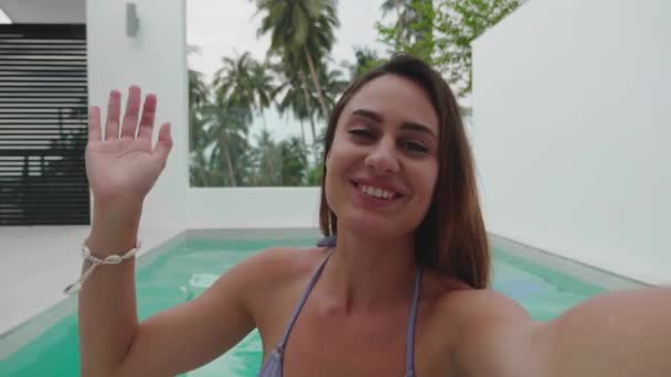 Jovem mulher feliz em vlogger vocação acenando mão olhando para webcam falando com câmera nadar em piscina vídeo conferência chamada em reunião de bate-papo virtual com amigo distância social. — Vídeo de Stock