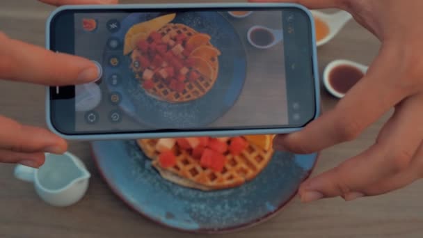 Akıllı telefonlu Top View yemek fotoğrafçılığı. Elleriyle Belçika Waffle 'larını tahta masa üzerinde karpuz parçalarıyla fotoğraflıyor. Yakın çekim.. — Stok video