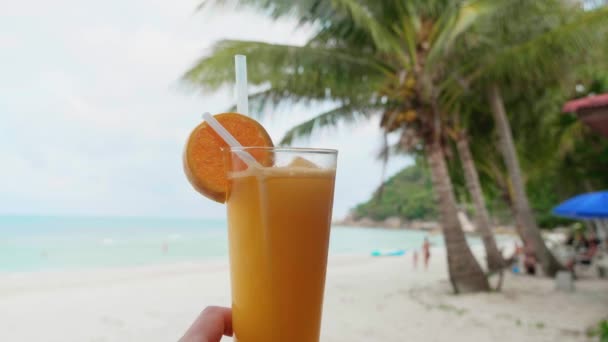 해변 해변에 있는 오렌지 주스나 오렌지 신선 한 주스를 즐기는 여름 서핑을 즐기는 사람들은 상쾌 한 음료를 마음껏 즐기며 즐거운 휴가를 보낸다 — 비디오