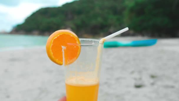 Тропічний свіжий казан у склянці з соломою на пляжі тримається за природне місце на задньому плані моря — стокове відео