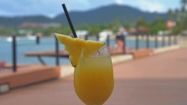 Teras ve okyanusun arka planında cam bardakta ananas suyu.