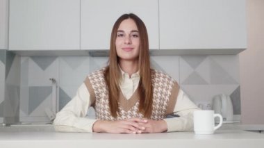 Tişörtlü ve yelekli kadın kameraya bakıyor, iş müşterisiyle internette sohbet ediyor. Video görüşmesi sırasında sorulara cevap veren akıllı, iş başvurusunda bulunan hoş bir bayan..