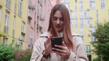 Kendine güveni tam bir iş kadını elinde akıllı telefonuyla caddede yürüyor. Kateterli ceketli güzel bir kariyer kızı şehirde dolaşıyor..