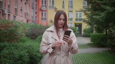 Kapalı portre endişeli genç kadın telefona bakıyor ve kötü haberleri görüyor. Korku içinde esmer bir kız akıllı telefonunda SMS okuyor. Dışarıda duruyor.