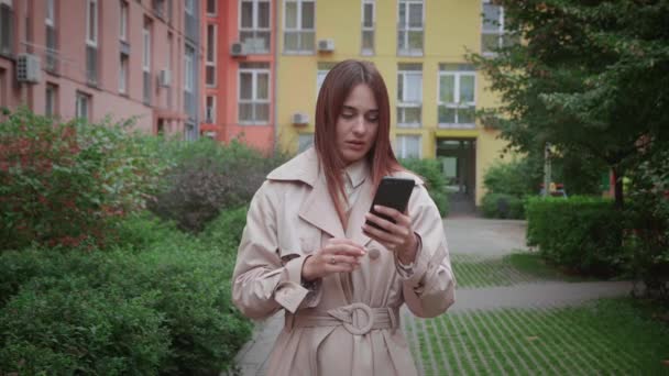 Zblízka portrét úzkostlivá mladá žena dívá na telefon vidí špatné zprávy. Bruneta dívka v hororu čtení sms na smartphone stojící venku — Stock video