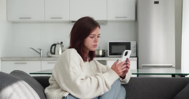 Retrato de una hermosa mujer caucásica joven molesta usando el teléfono inteligente en casa — Vídeo de stock