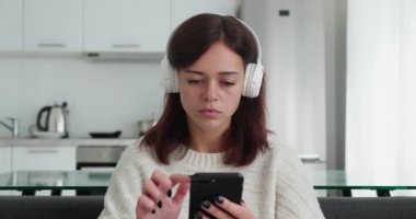 Kulaklıklı güzel bir genç kız sosyal medyada arkadaşlarıyla sohbet ederken cevap verirken iş yerinde oturuyor.