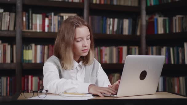 Studia online w klasie wirtualnej z nauczycielem przez połączenie wideokonferencyjne, oglądanie lekcji telewizji na laptopie w bibliotece domowej, w klasie. Dobre wieści. — Wideo stockowe