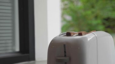 Kızarmış ekmek tost makinesinden fırlarken duman çıkıyor. Tost makinesinden fırlayan iki tost parçası.
