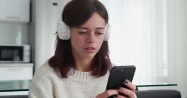 Bin yıllık kulaklıklı kadın cep telefonu kullanıyor ve gülümsüyor. Vay canına dedi.