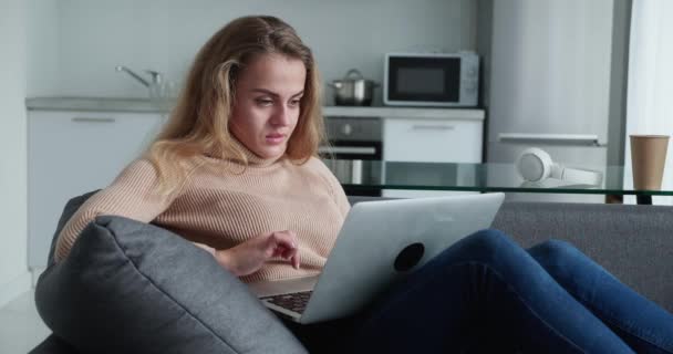 Vooraanzicht. Aantrekkelijk blond meisje zegt wow in verrassing tijdens het kijken op het scherm laptop — Stockvideo