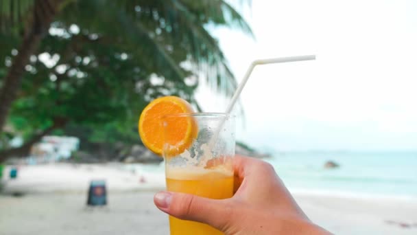 エキゾチックなビーチでテーブルの上のガラスのトロピカルフルーツから新鮮なジュース,閉じる — ストック動画