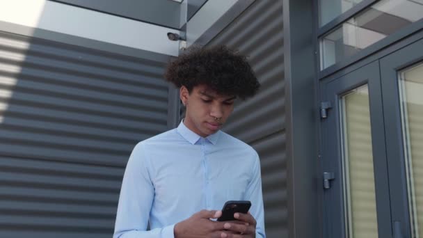 Jonge zakenman loopt op straat te sms 'en — Stockvideo