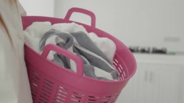 Kirli çamaşırlarla dolu sepeti tutan genç bir kadın, yakın plan..