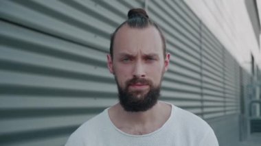 Mutsuz, ciddi, mavi gözlü bir adam kafasını sallayarak hayır diyor ve tasvip etmediğini ifade ediyor. Binanın arka planına karşı sıradan beyaz bir süveter giydiğini reddediyor. İnkar kavramı