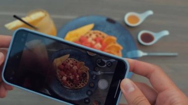 Kadın eli restoranda akıllı telefonla iştah açıcı yiyeceklerin fotoğrafını çekiyor. Eski stil