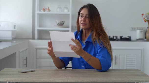 Красивая женщина открывает свою почту и получает хорошие новости — стоковое видео