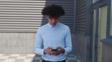 Genç Çekici Adam cep telefonunu kullanırken kasabada yürüyor. Smartphone tutmak, Networks 'de sörf yapmak. Modern Teknoloji ve İletişim. 