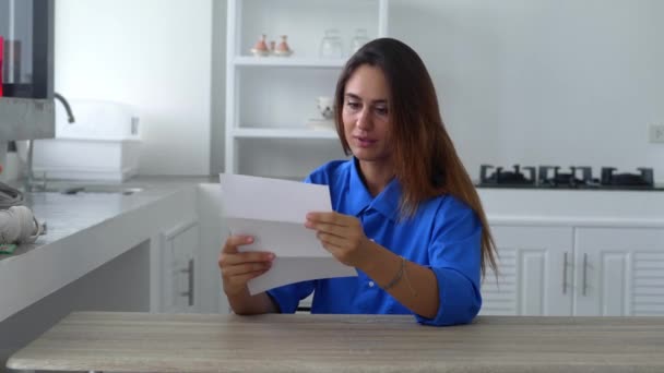 Happy attractive young woman reading pleasant news in letter postal correspondence, feeling excited of getting event invitation or university admission post notification. — стоковое видео