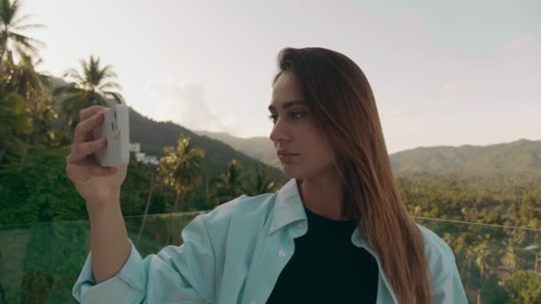 Gelukkige toerist draait in een richting om een panorama van het actuele bos te nemen met haar smartphone onder de blauwe hemel in een landelijk gebied — Stockvideo