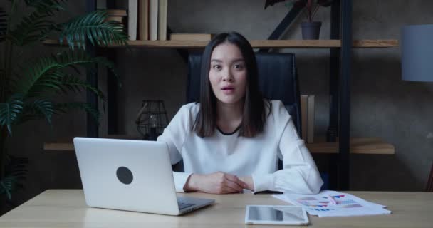 Surprise femme d'affaires asiatique regarde la caméra dans la surprise et dit wow tout en étant assis dans le bureau. Une étudiante choquée en chemises blanches formelles se réjouit de la bonne nouvelle, à l'intérieur — Video