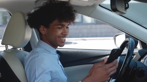 Young, business guy of ethnicity scrolls the news feed on the smartphone while sitting in the car. Business is about traveling and making connections — Vídeo de stock