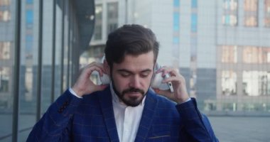 Joyful male in suit have good mood in headphones enjoying songs in town. Close up portrait. Leisure concept