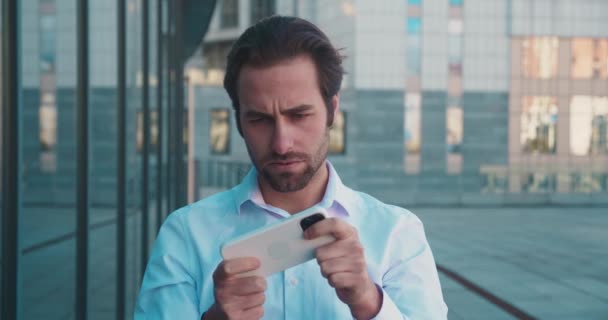 Takım Elbiseli Adam Oyunda Akıllı Telefonda Oynuyor Şehir Arka Planında — Stok video