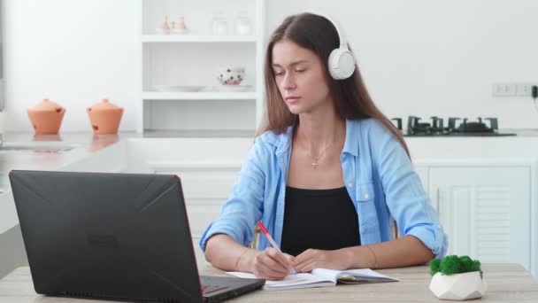 Фокусована Студентка Навушниками Пишуть Нотатки Ноутбуці Перевіряє Резюме Почерку Дивиться — стокове відео