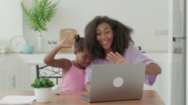 Cute mother and daughter using laptop, make video call, communicates online with family memberships across the distance