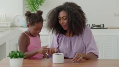 Loving mother and daughter count coins and throw them into the piggy bank, collect money for purchase, for travel