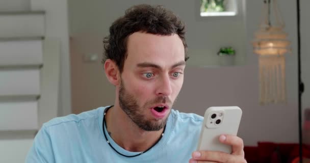 Handsome Guy Has Fun Home Expressing Surprised Emotion While Scrolling — Vídeo de Stock