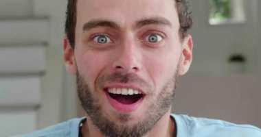 Headshot. European bearded man putting off his eyeglasses when looking at camera with surprised sincere emotions