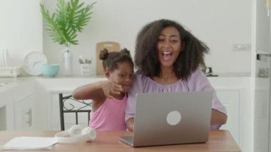 Multi-ethnic family of two, mom and daughter waving with hands while having a video call. Online communication concept