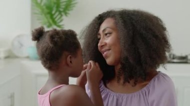 Close-up adorable little girl stroking her moms hair, hugging her with love and tenderness, enjoying pastime together