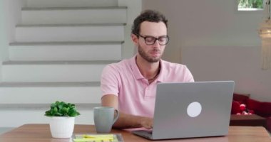 Successful Caucasian man, programmer writing computer programs, working remotely on laptop in comfortable home office.