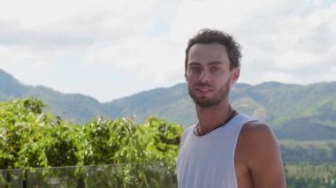 Half-length portrait. Peaceful young man breathing fresh air during morning yoga, enjoying amazing view from his balcony