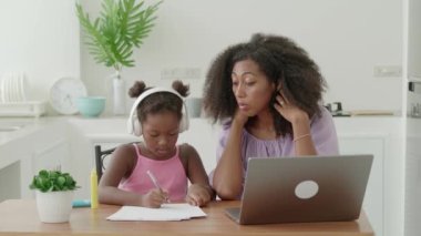 Young experienced multi-national female tutor is engaged in lessons at home with a little girl, preschooler child