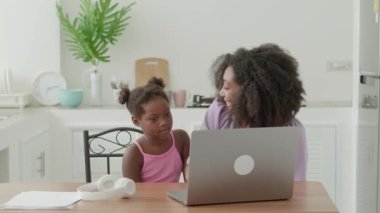 Beautiful multi-ethnic and her cute child are communicating together and expressing surprise, looking at laptop monitor